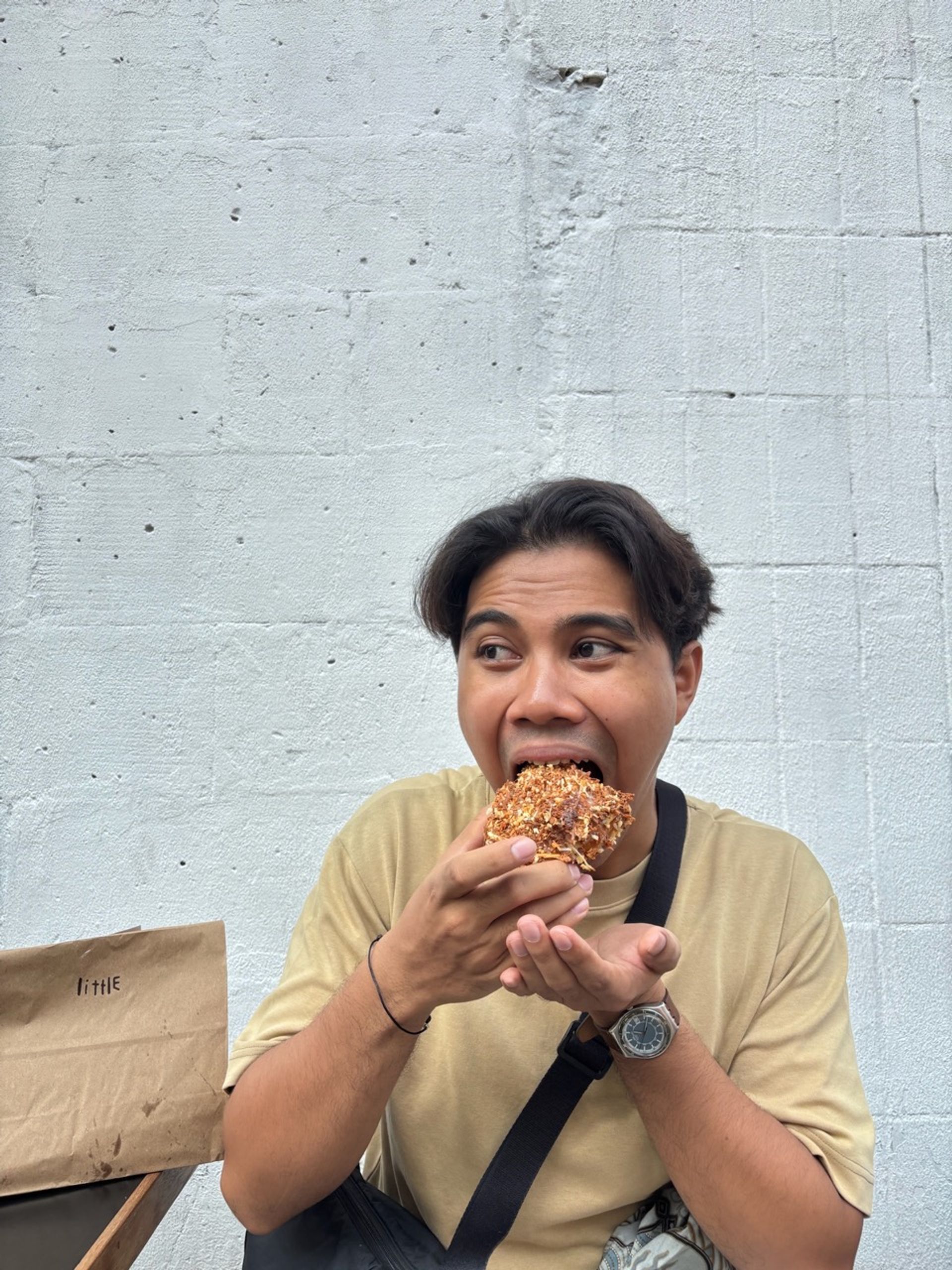 a man eating a donut in front of a white wall with a bag that says the on it