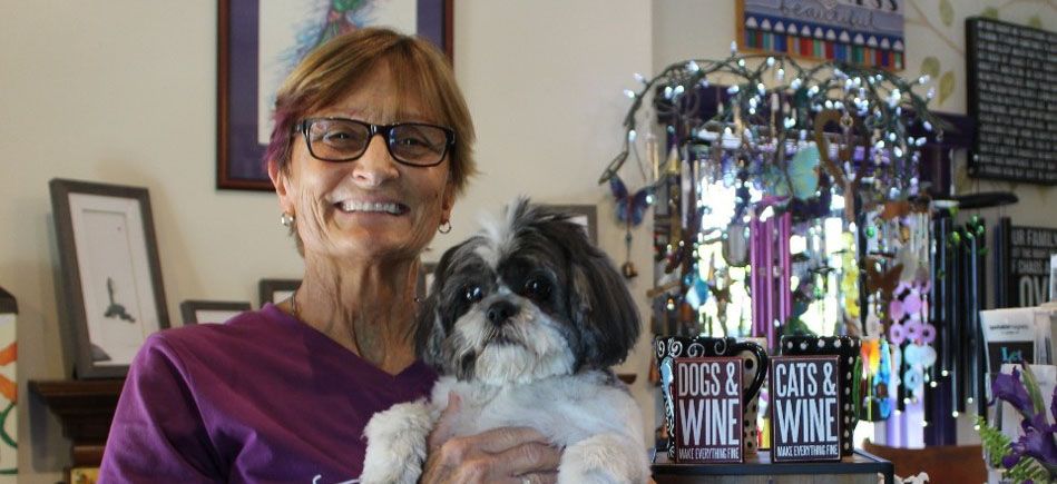 The photo shows Sue in her purple shirt with current pet named Beau.