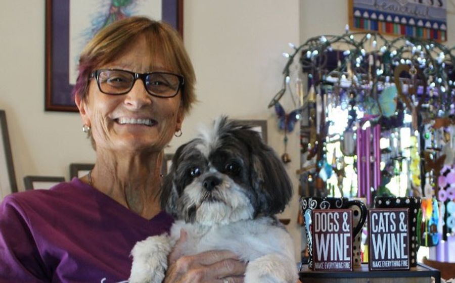 The photo shows Sue in her purple shirt with current pet named Beau.