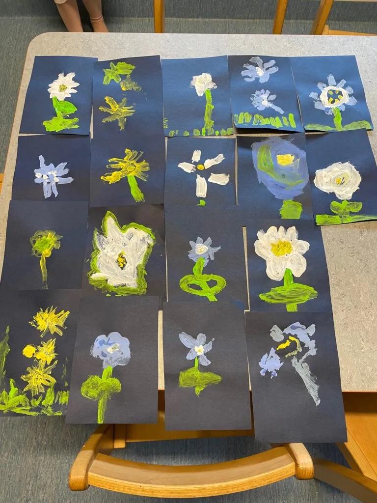 Barnens blomstermålningar på blått papper