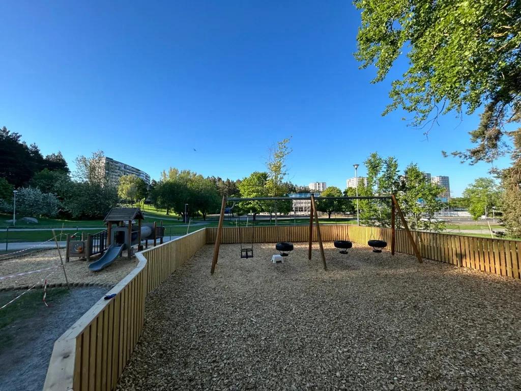 Gungorna på gården med grönskande park bakom