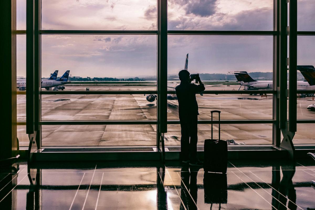 A traveller photographing a plane through an airport window