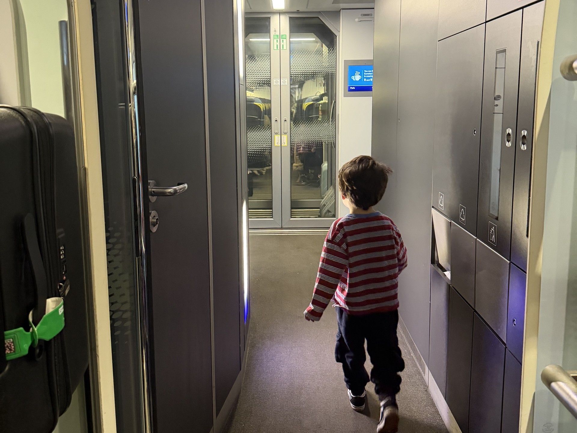 Young child walks down a hallway toward elevators, seen from behind