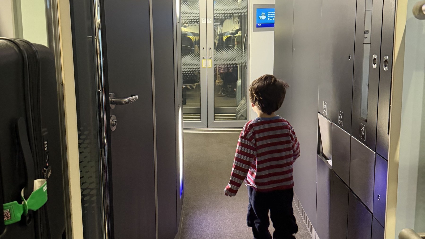Young child walks down a hallway toward elevators, seen from behind