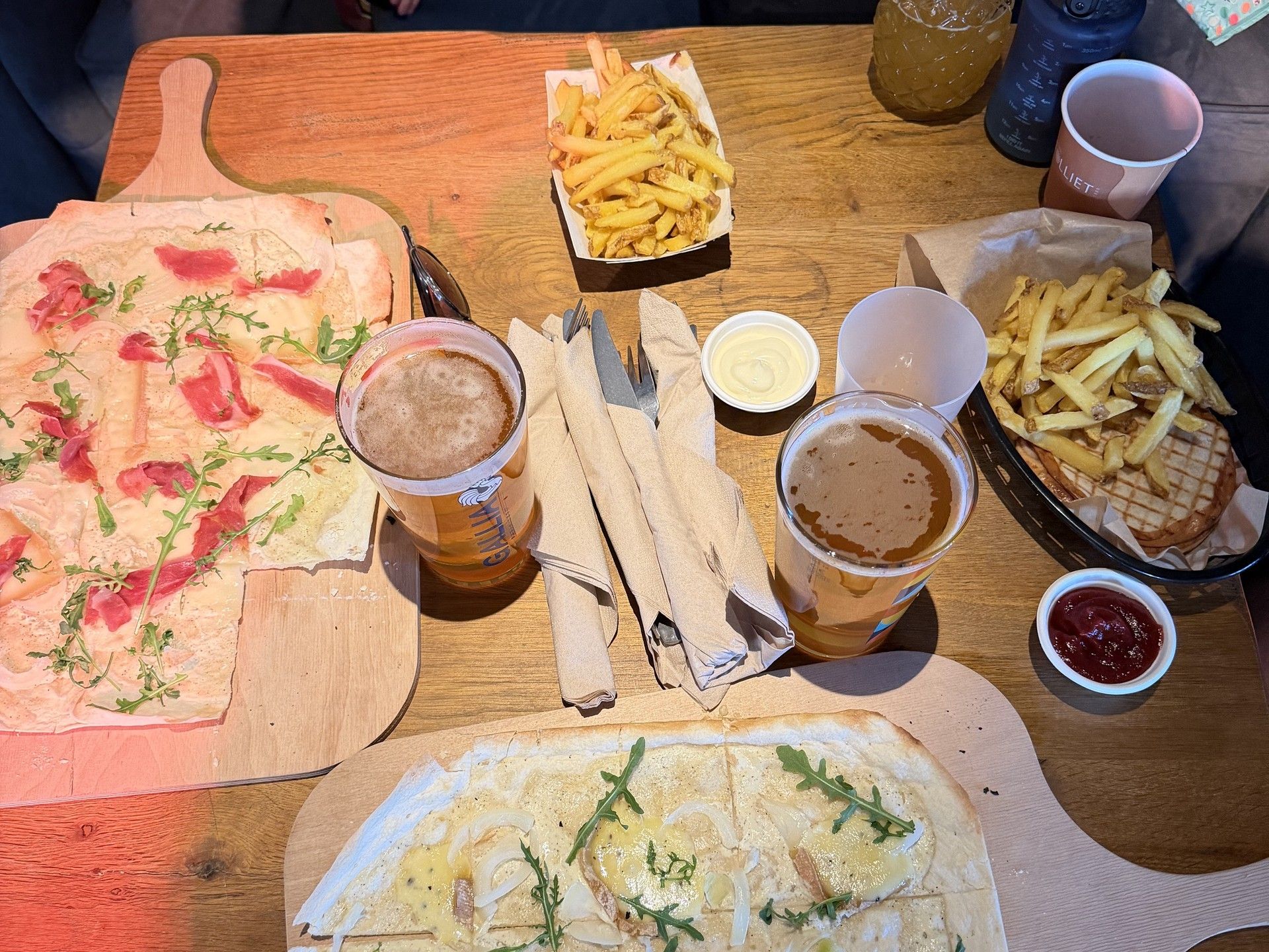 Après-ski snack spread on wooden table with fries, dips, drinks, and flatbread