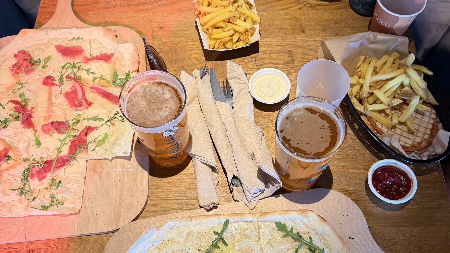 Après-ski snack spread on wooden table with fries, dips, drinks, and flatbread