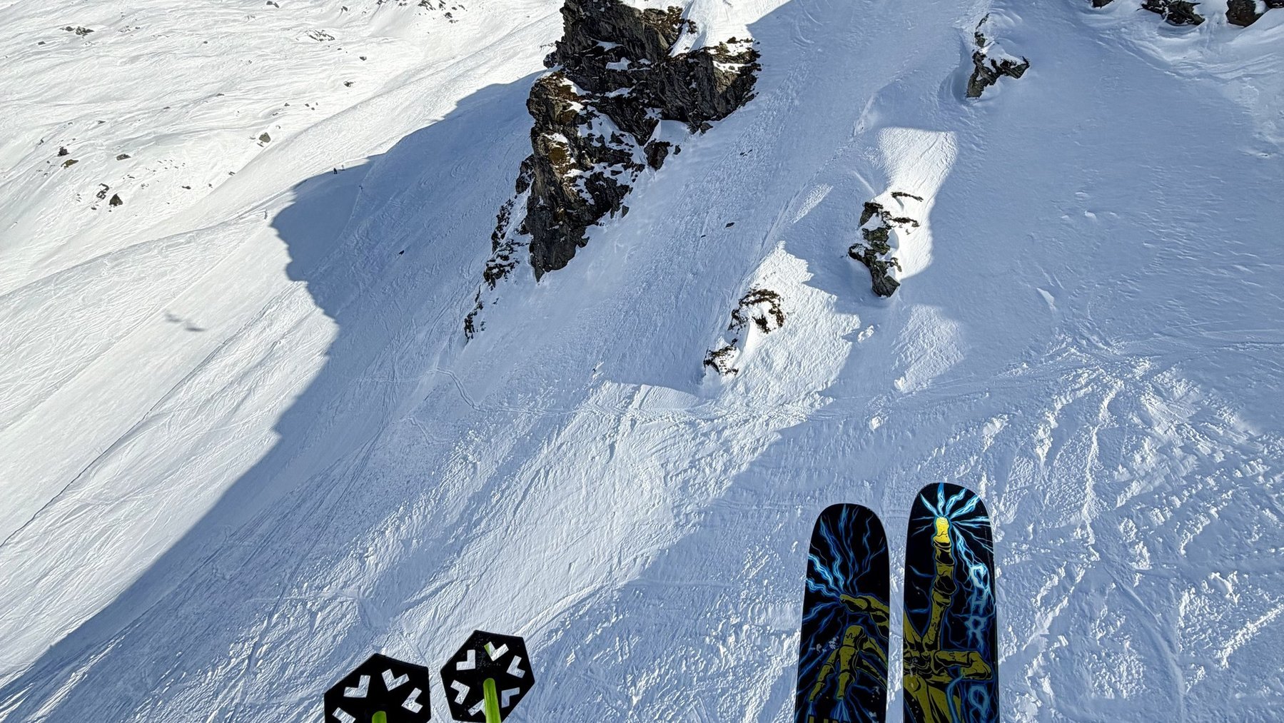 Skier’s skis and poles point uphill toward a lift on a steep, snowy slope at La Rosière