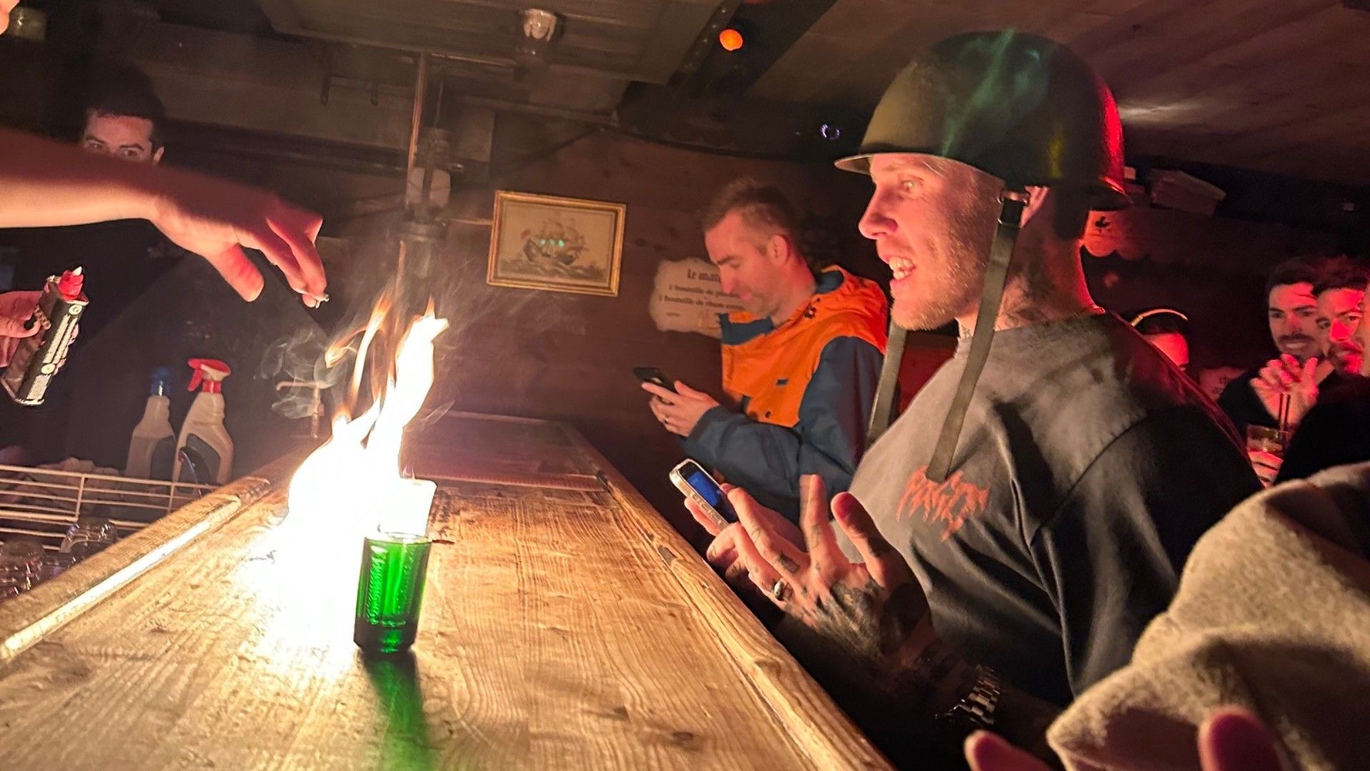 Skiers in helmets gather around a wooden bar during a lively après-ski celebration