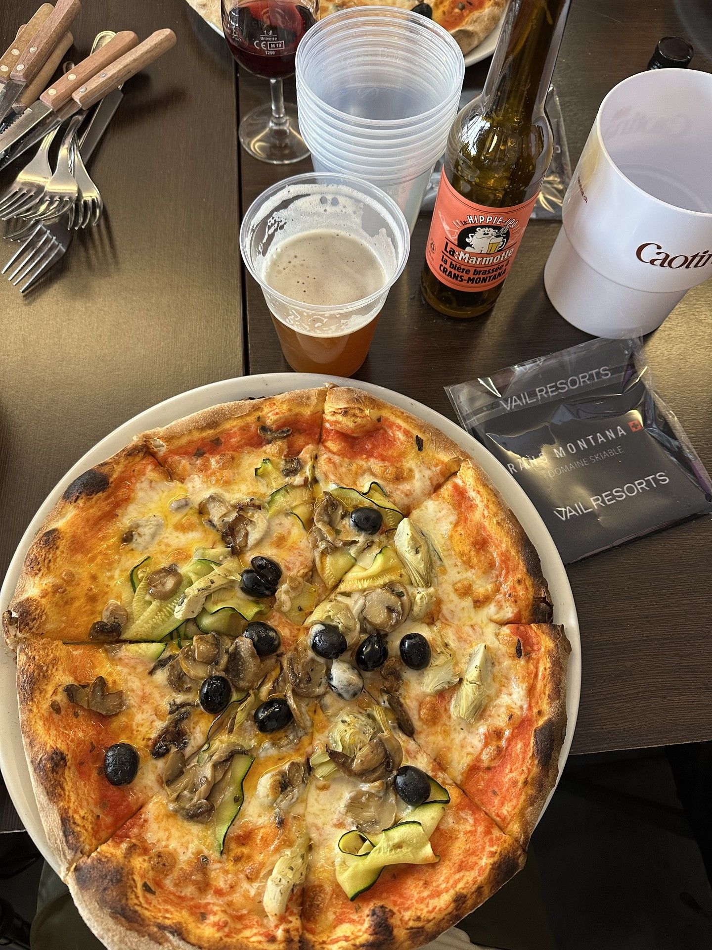 Stone-baked pizza on a table with drinks and water at a ski resort restaurant.