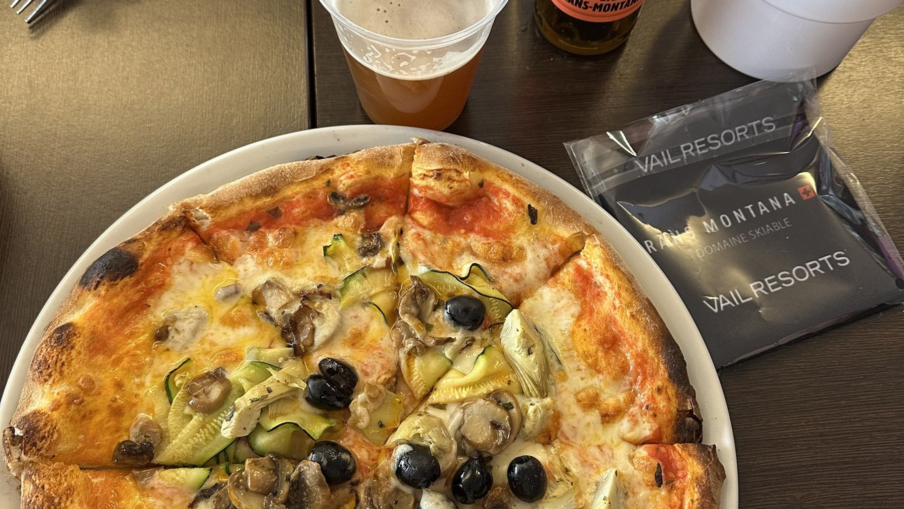 Stone-baked pizza on a table with drinks and water at a ski resort restaurant.