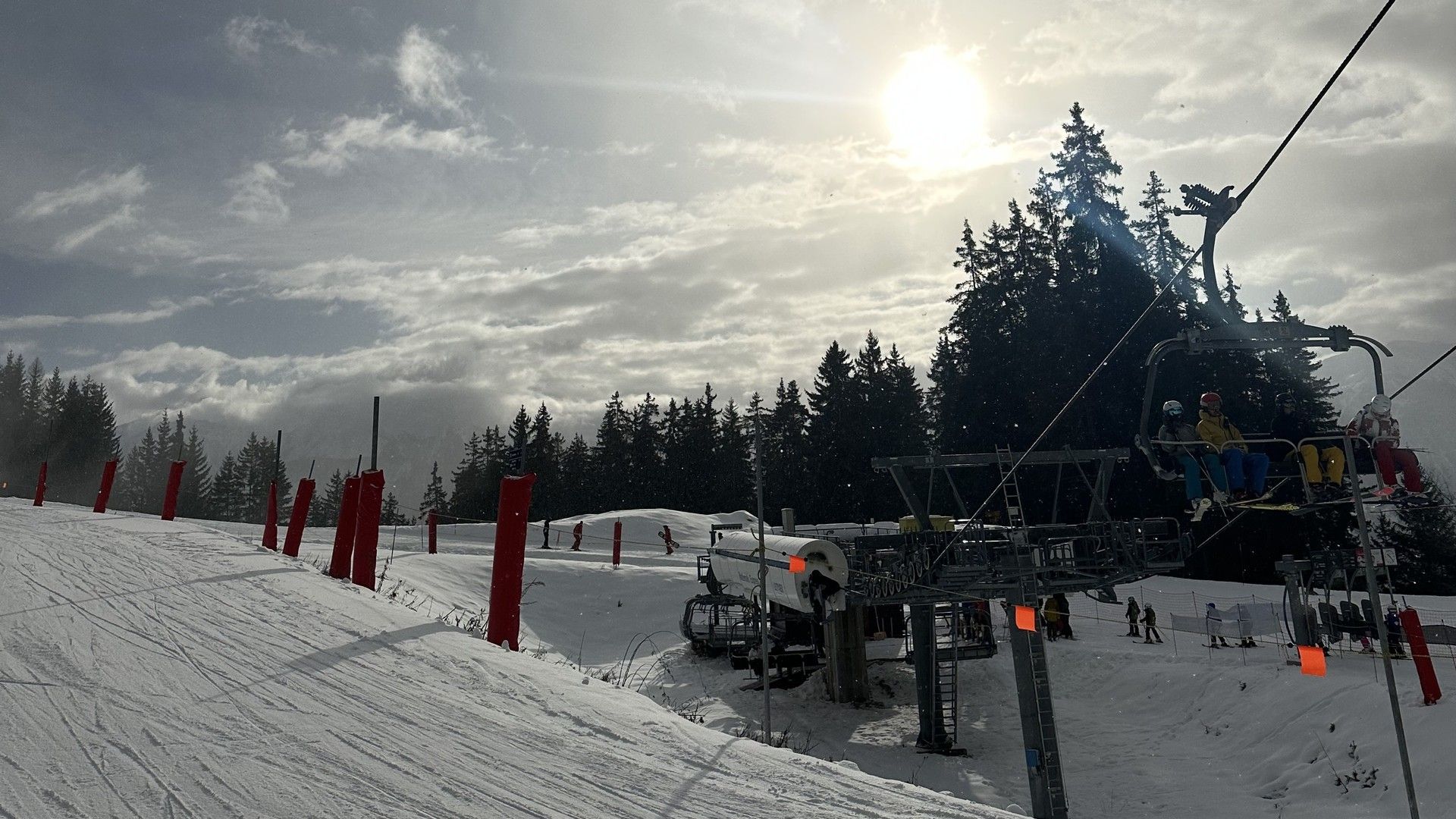Ski slope under cloudy skies with a chairlift running and skiers preparing to descend