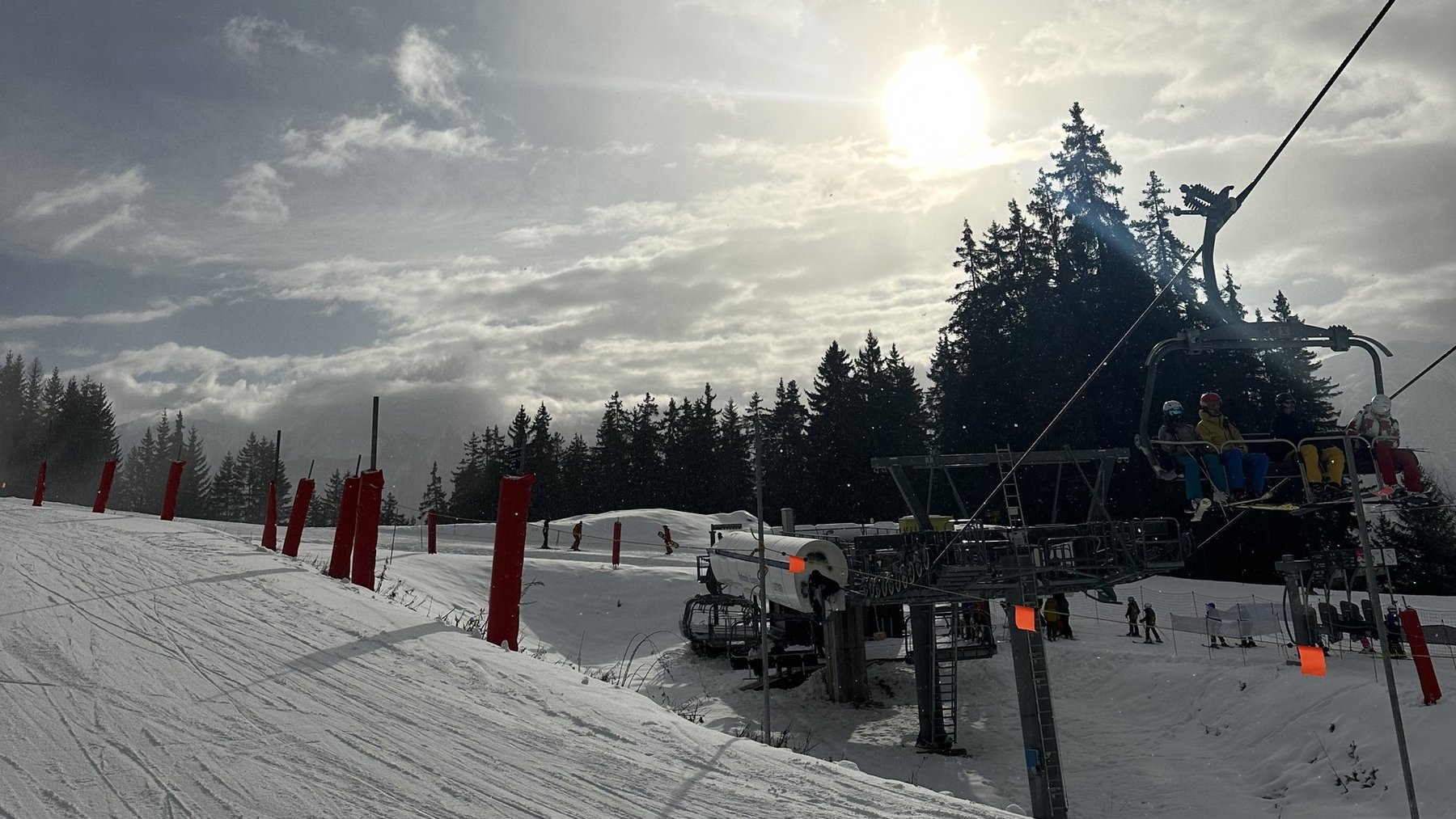Ski slope under cloudy skies with a chairlift running and skiers preparing to descend
