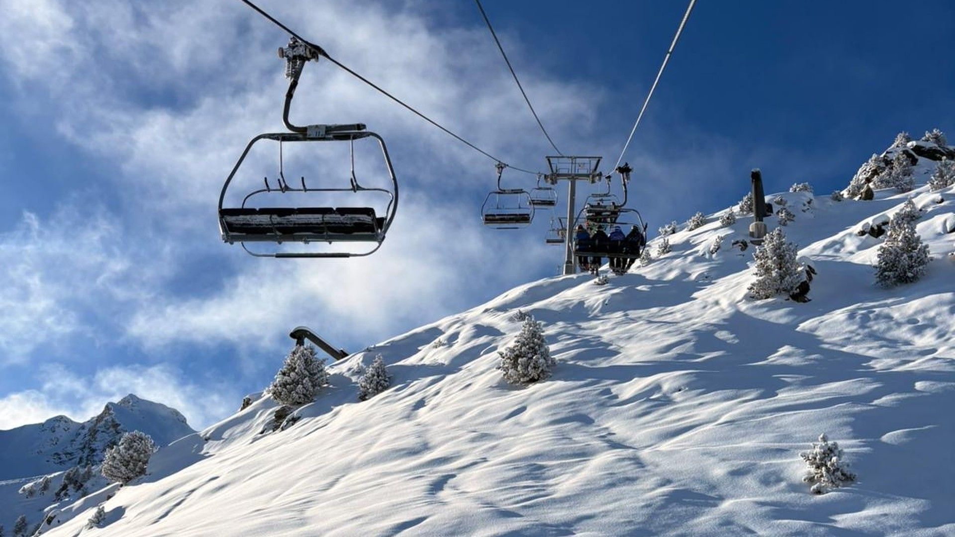 A chairlift rises over a snow-covered slope in Courchevel beneath a deep blue sky.
