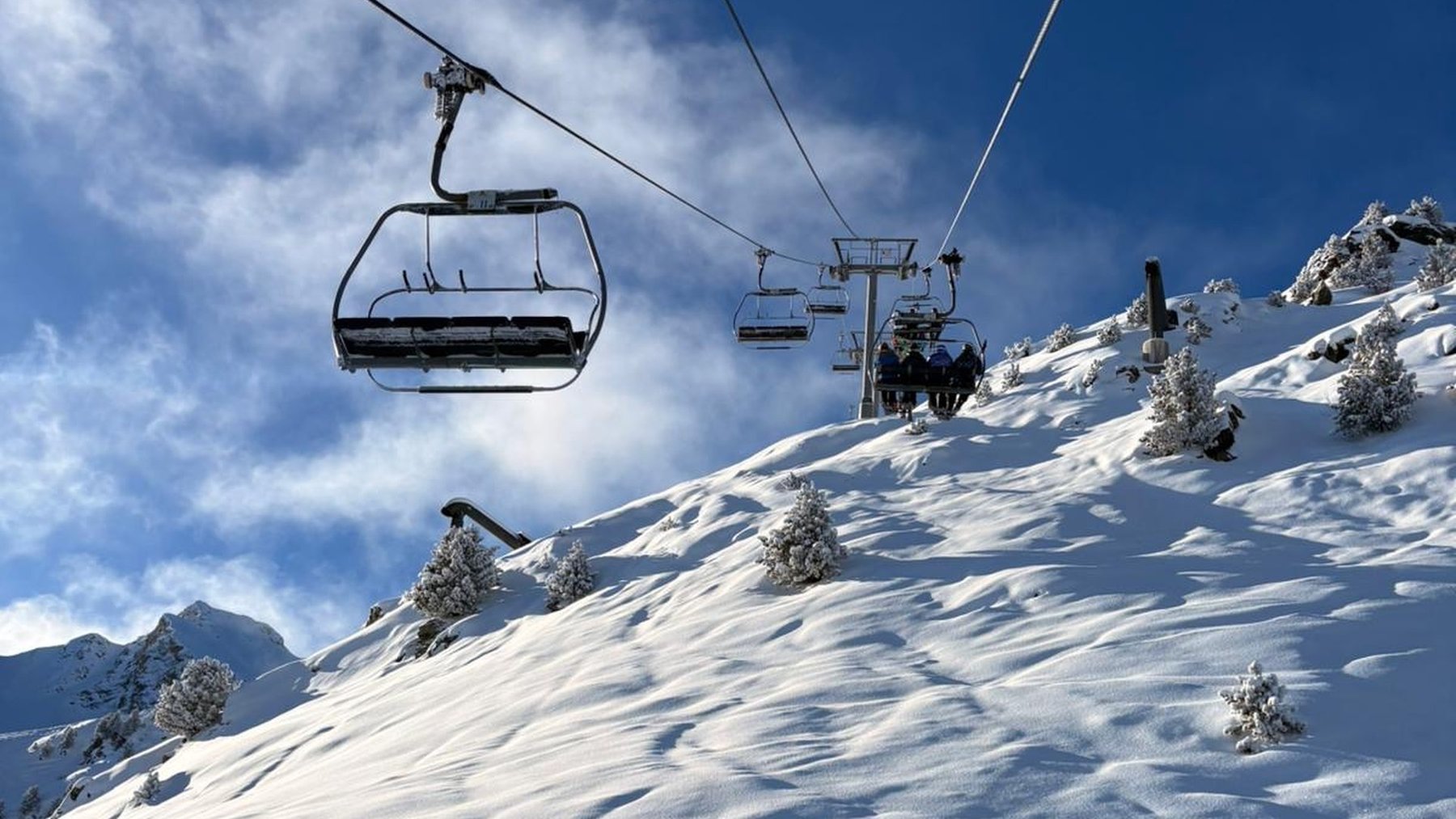 A chairlift rises over a snow-covered slope in Courchevel beneath a deep blue sky.