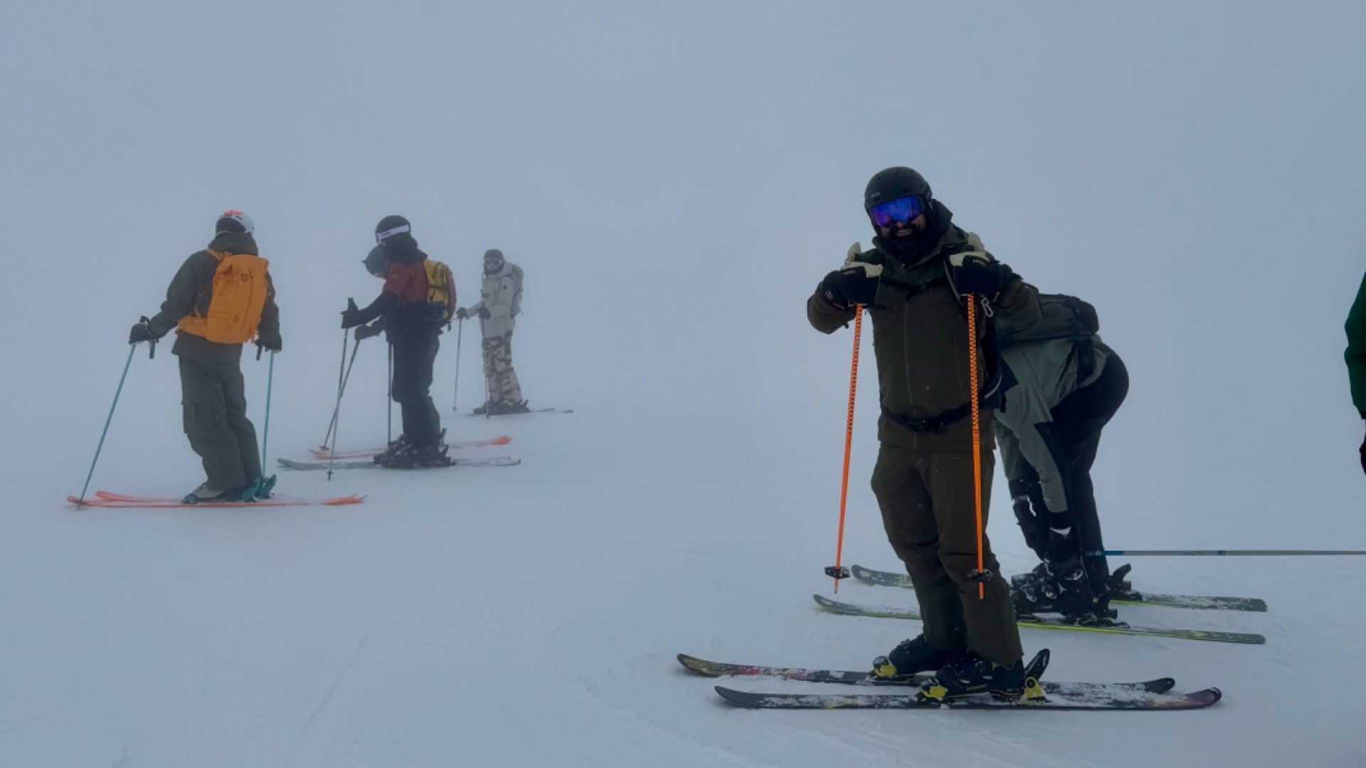 Skiers descend a foggy, snow-covered slope in Courchevel, with a group following behind.