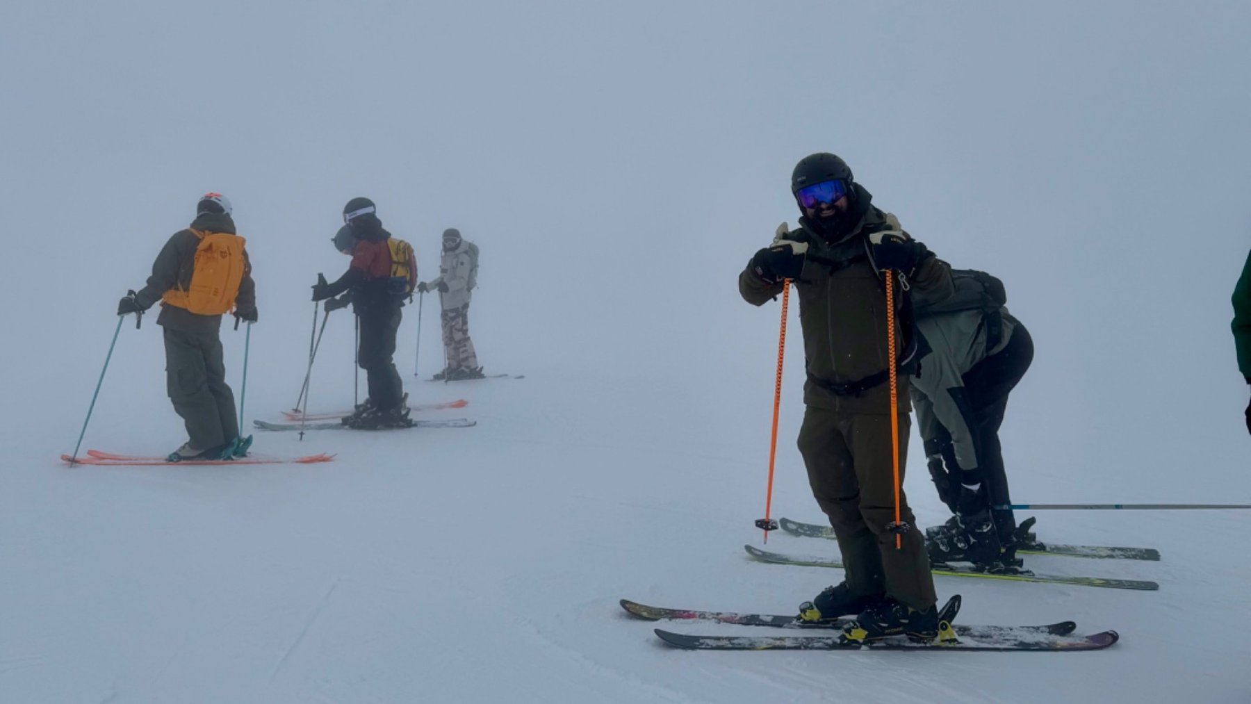Skiers descend a foggy, snow-covered slope in Courchevel, with a group following behind.