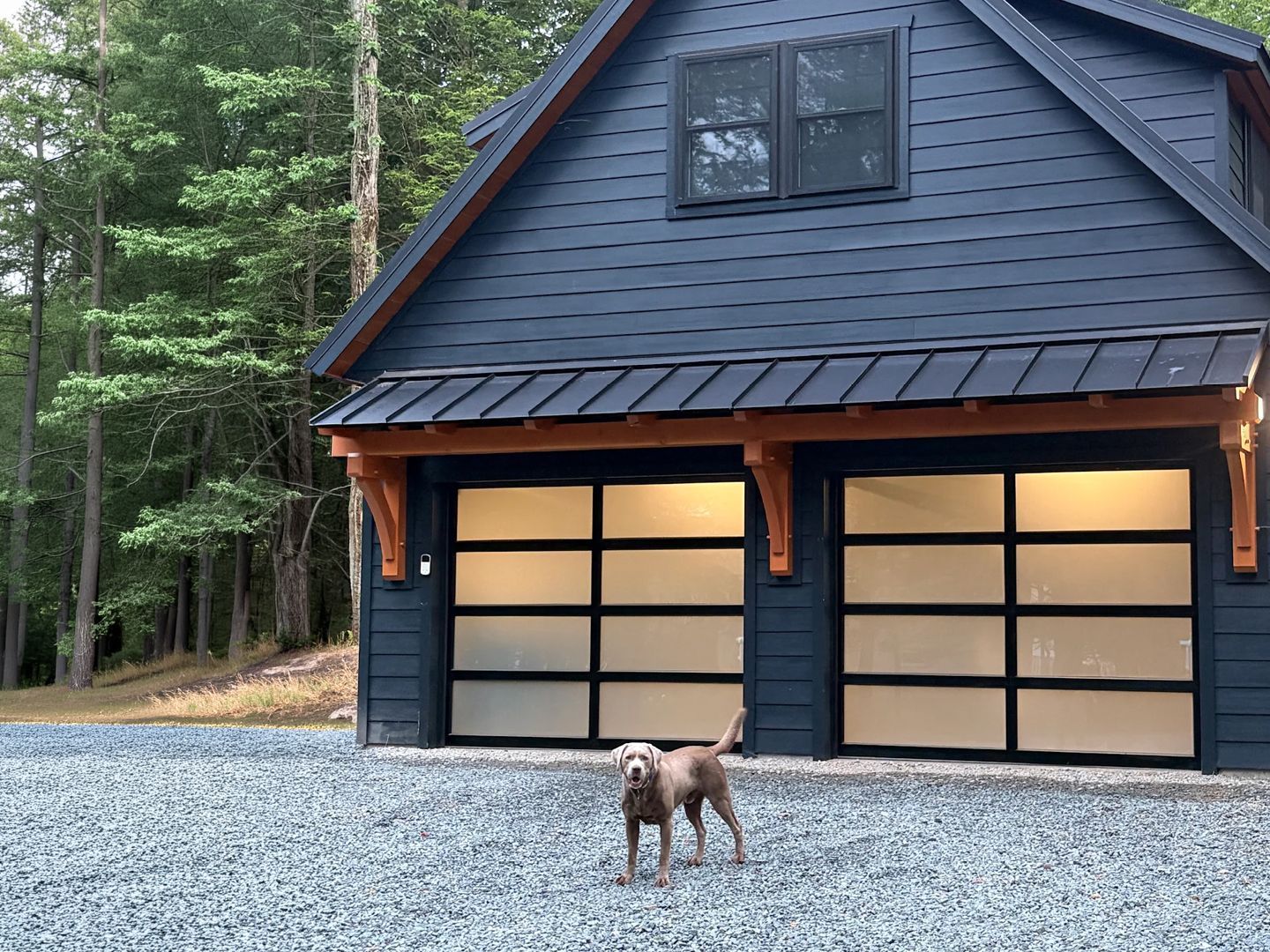 Two-car garage with a loft, dark siding and frosted glass doors
