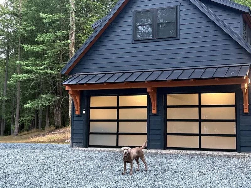 Two-car garage with a loft, dark siding and frosted glass doors