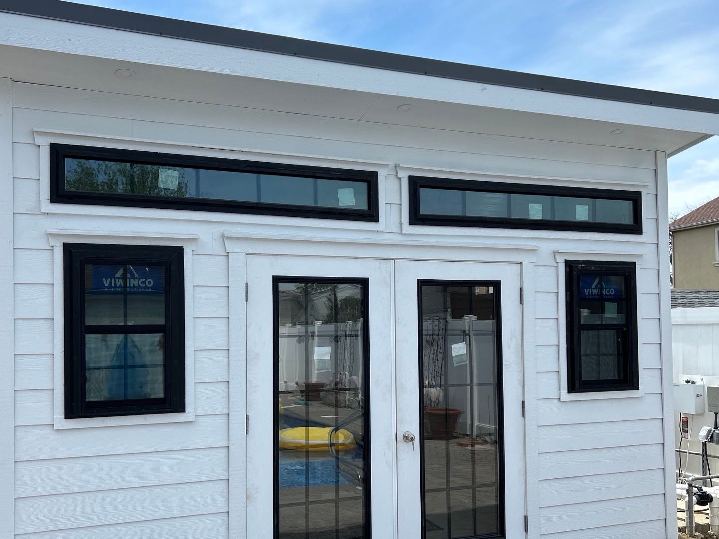 White pool house with French doors and a row of transom windows