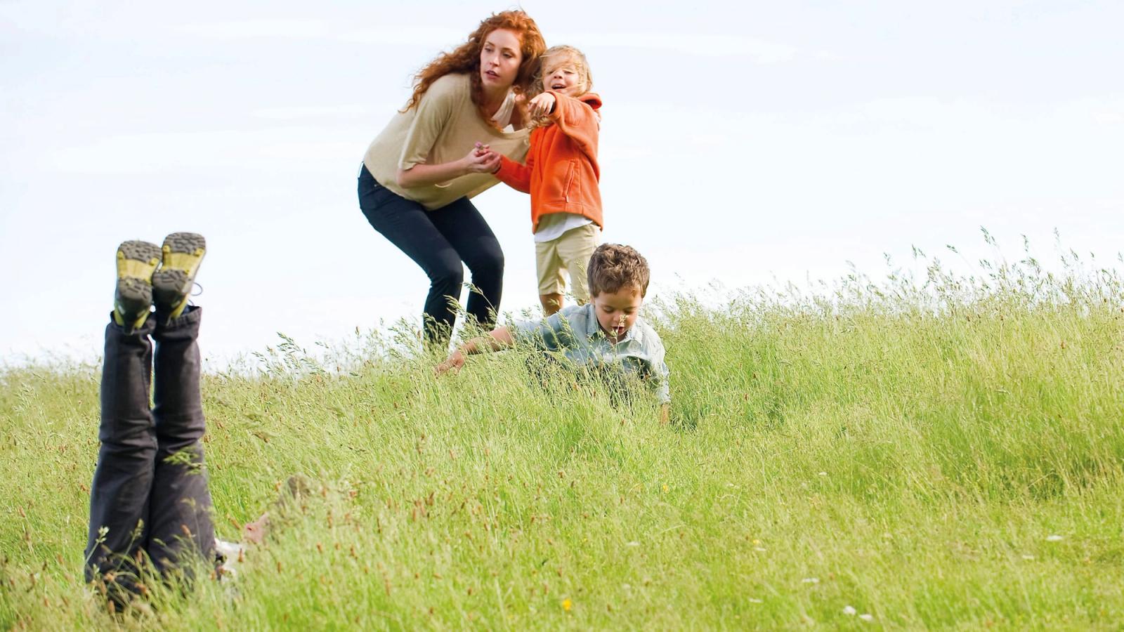 PACEY image showing a woman outside at the top of a hill bent next to a child in an orange hoodie pointing down the hill.