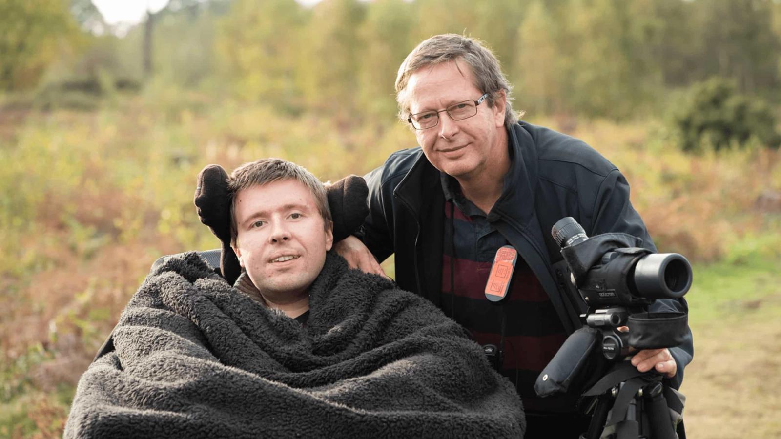 Wheelchair user and carer in the countryside with specialist binocular equipment.