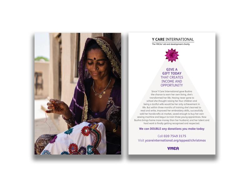 Y Care International appeal postcard front and reverse showing a smiling Indian woman wearing beautiful embroidered purple and gold sari sat on a step outside a sandstone house looking down sewing a piece of embroidered cloth to the front, and the reverse with the caption "Give a gift today that creates income and opportunity".