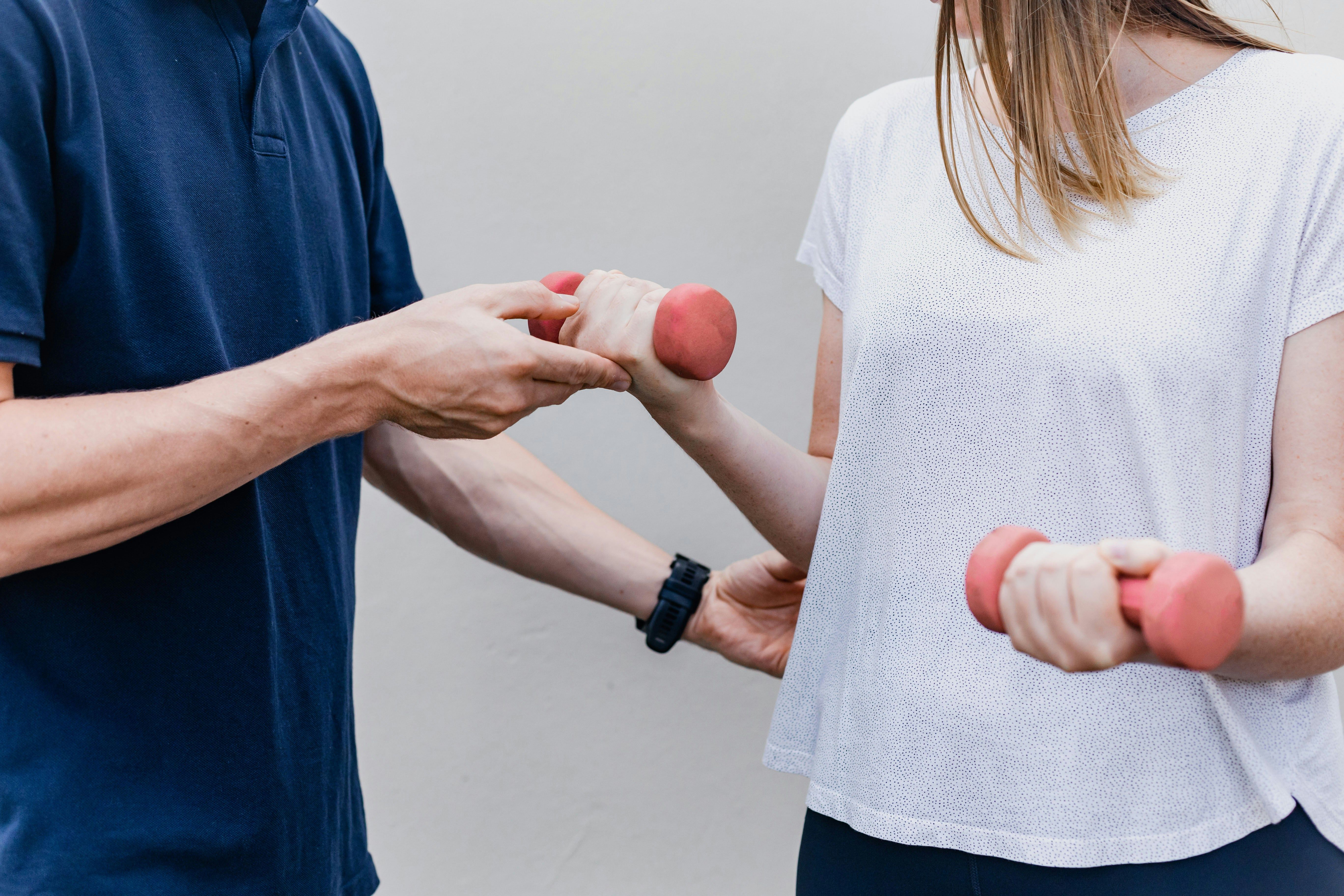 A therapist guides a participant through a strength exercise using hand weights.