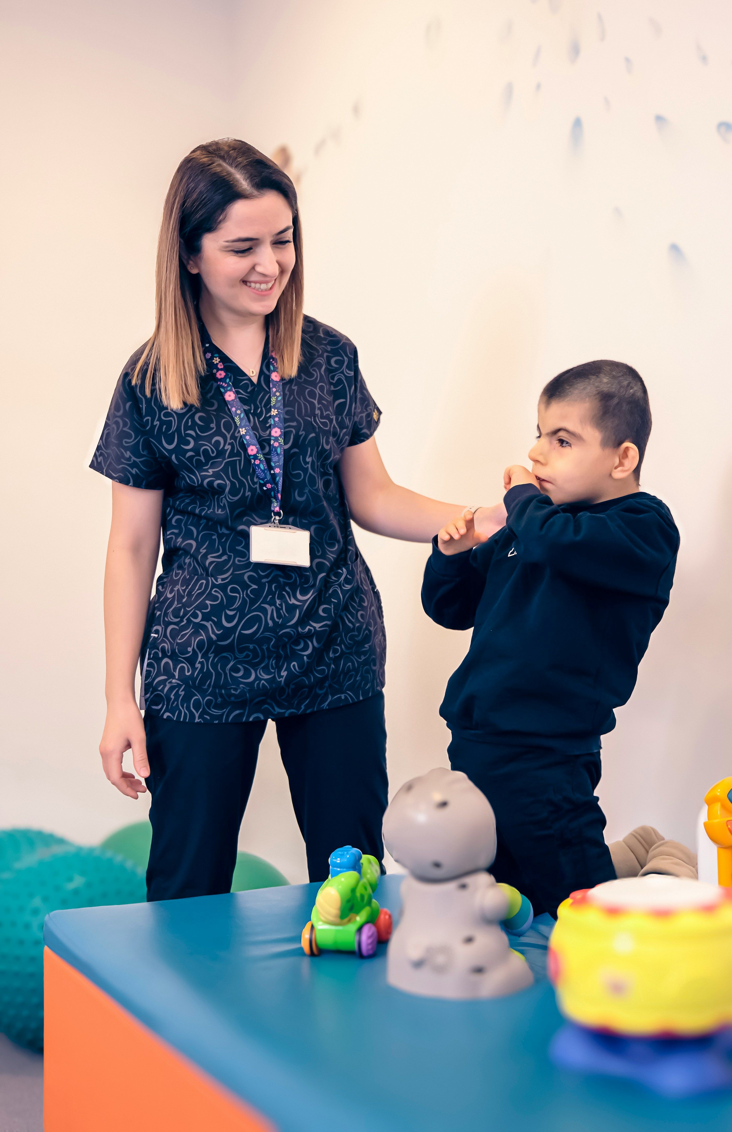A support worker assists a child during a play-based therapy session with sensory toys.