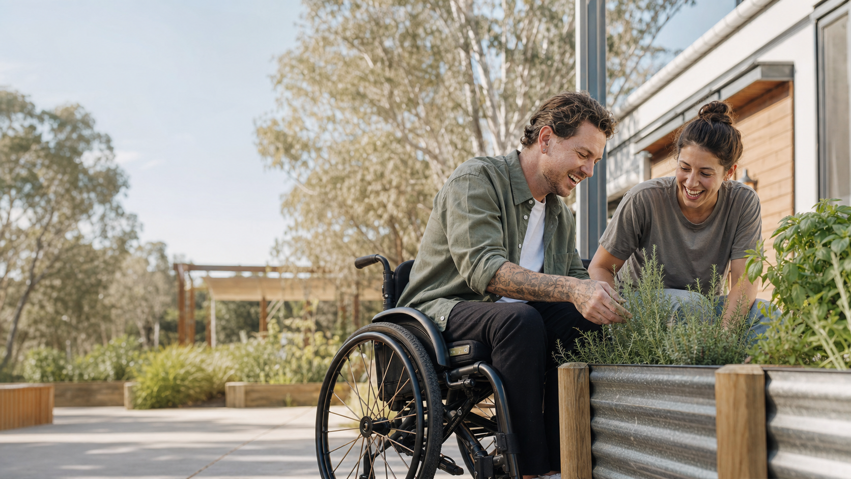 NDIS participant using a wheelchair and a support worker tending herbs together in a sunny, accessible Australian community garden.