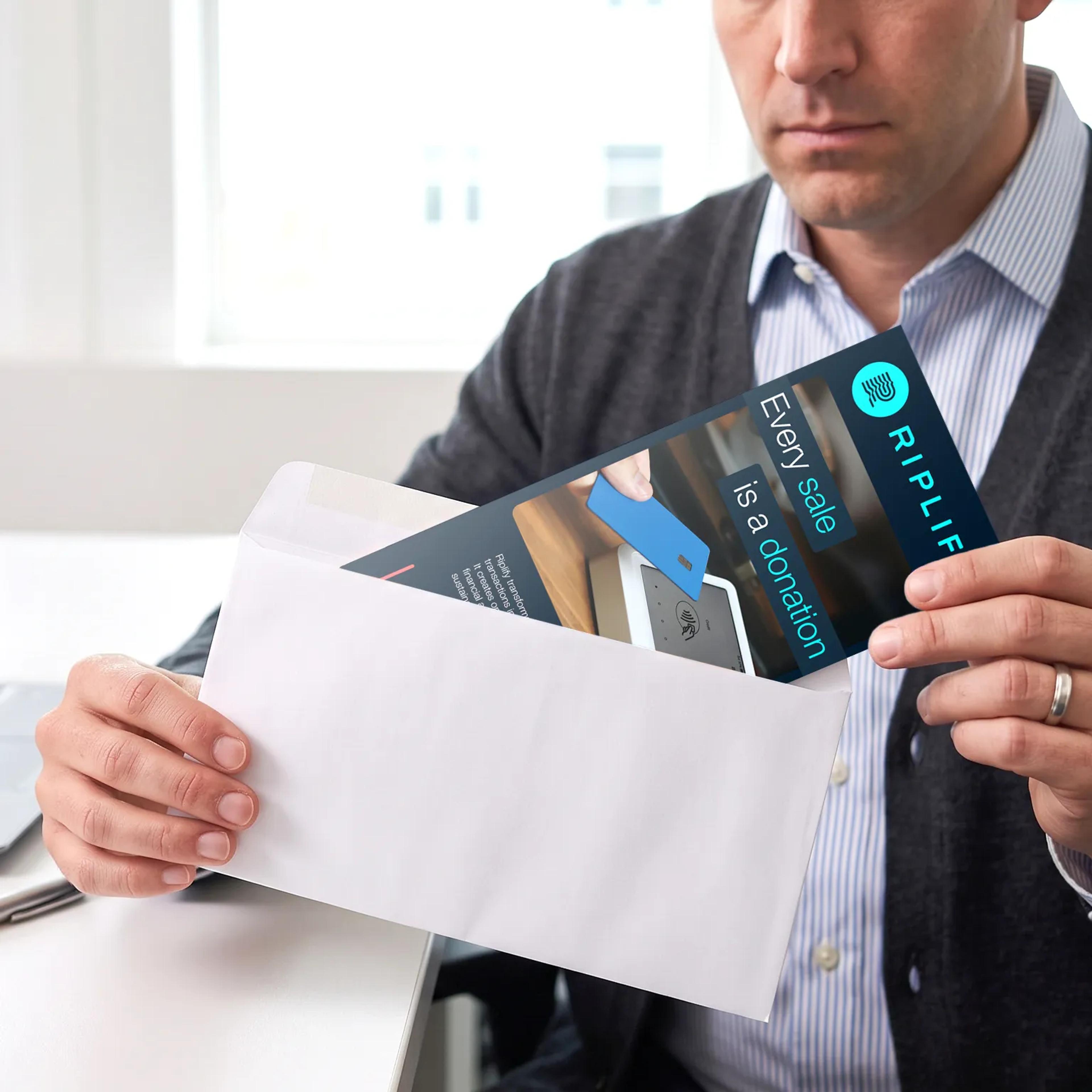 A man putting a Riplify trifold into a envelope