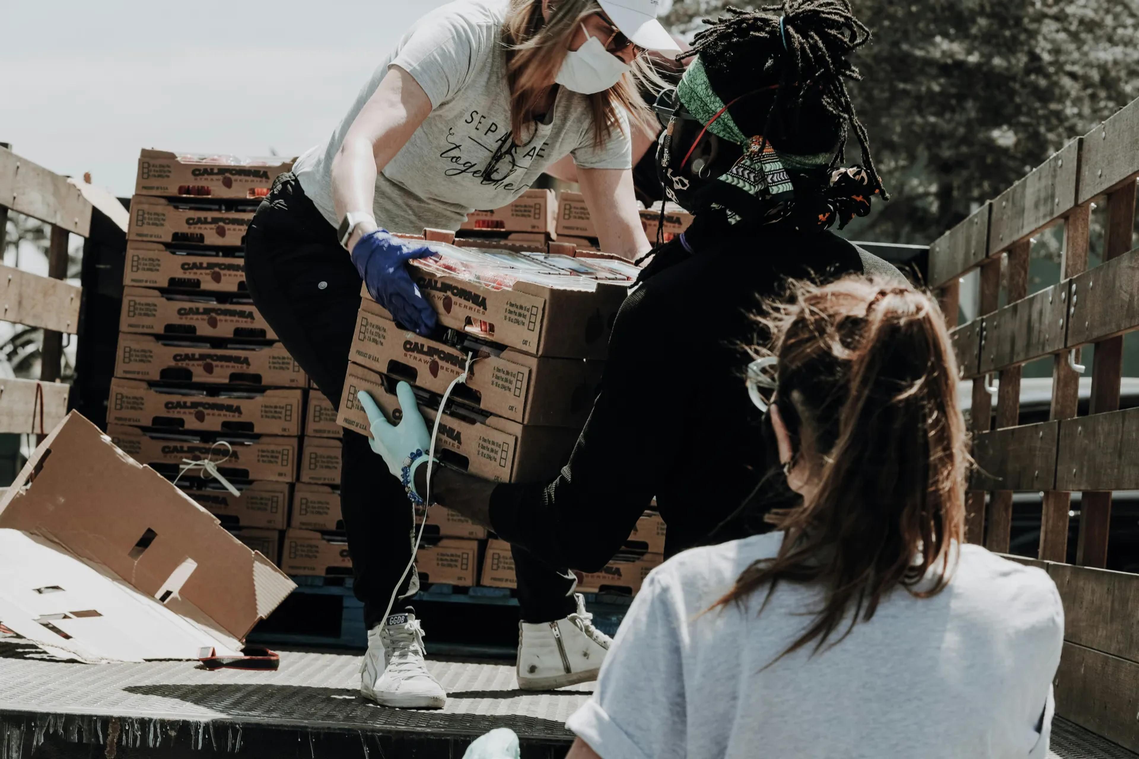 People passing boxes of food off of a truck