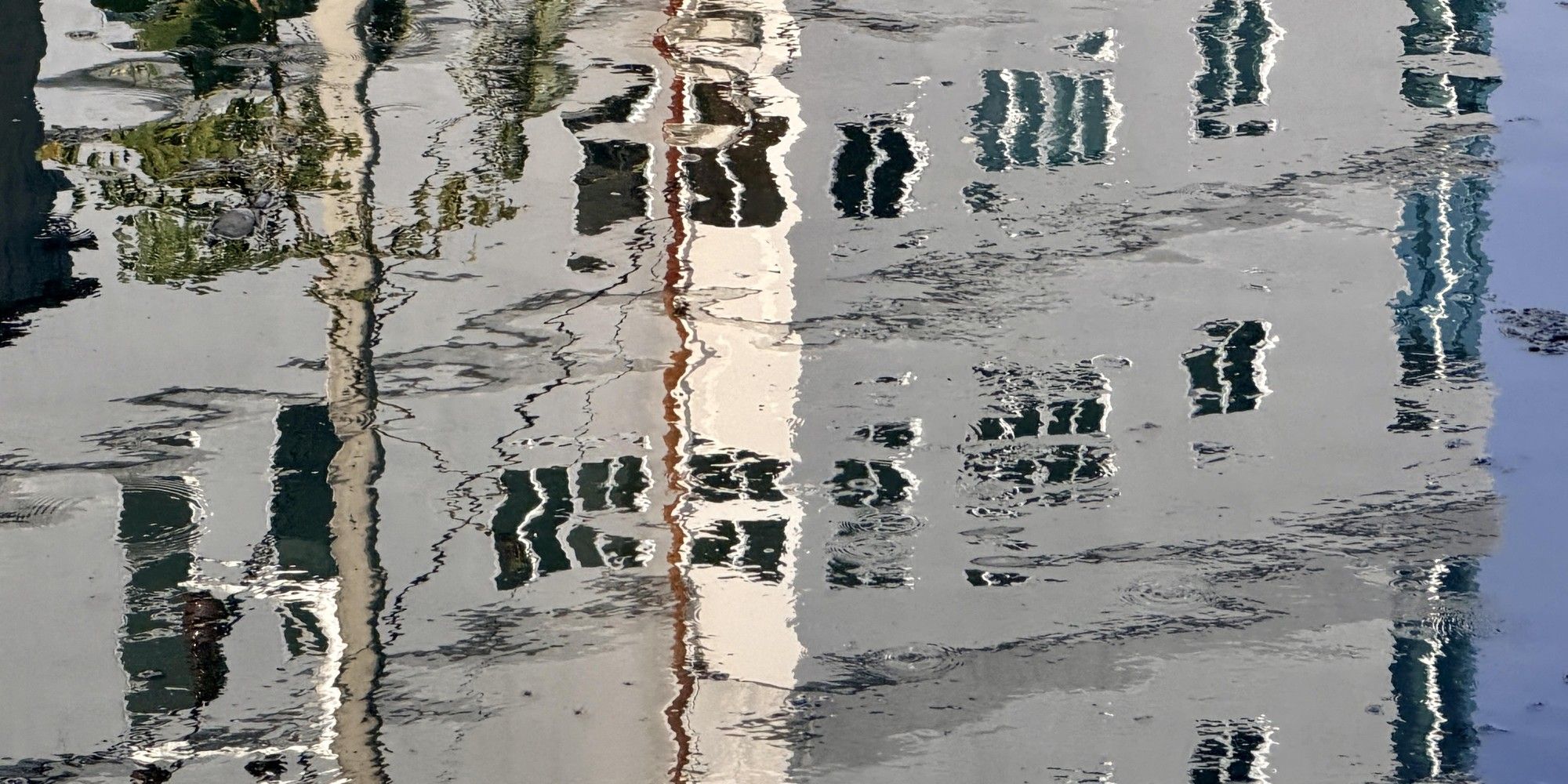 Black-and-white rippling water reflecting distorted tall buildings, standing for the unclear picture that emerges before scaling AI.