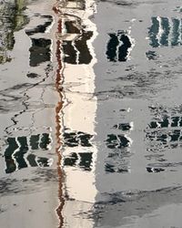 Black-and-white rippling water reflecting distorted tall buildings, standing for the unclear picture that emerges before scaling AI.