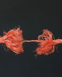 An orange rope frayed almost through, its two ends held together by a few thin strands against a dark background, standing for a customer relationship close to breaking.