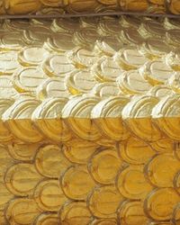 Rows of overlapping gold-painted scale-shaped relief tiles on a curved surface, evoking the layered costs hidden beneath a tempting free shipping offer.