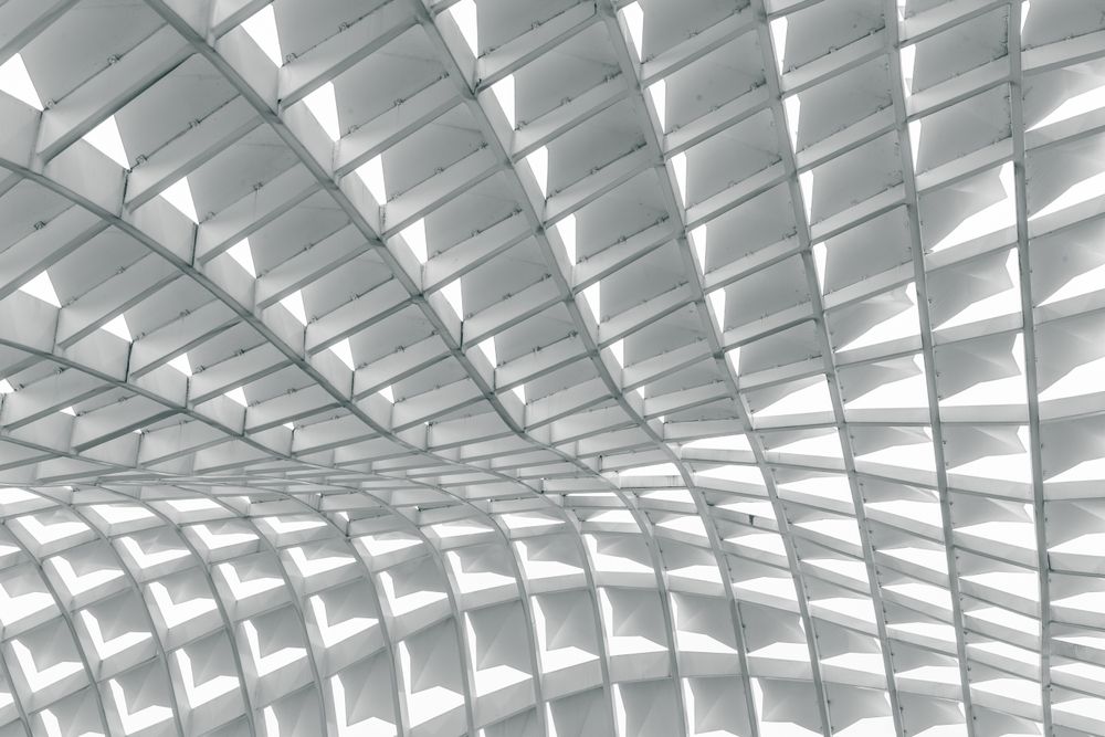 High-contrast architectural photograph of a curving white structural grid ceiling, serving as a visual metaphor for the recommendation surface and choice networks inside generative AI answers.