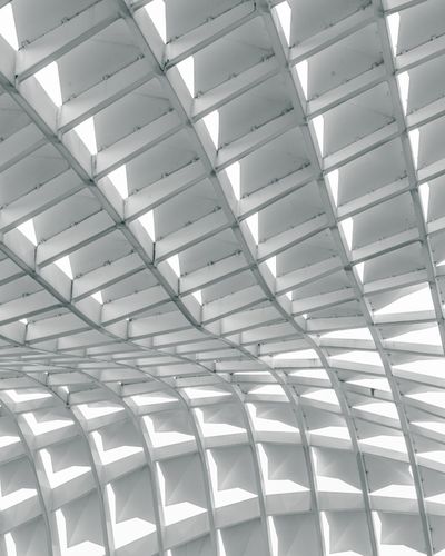 High-contrast architectural photograph of a curving white structural grid ceiling, serving as a visual metaphor for the recommendation surface and choice networks inside generative AI answers.