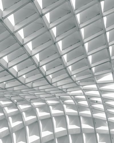 High-contrast architectural photograph of a curving white structural grid ceiling, serving as a visual metaphor for the recommendation surface and choice networks inside generative AI answers.