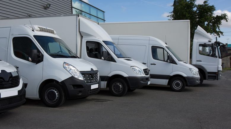 Fleet of white commercial vans parked outside Irish business premises — ideal for delivery companies seeking van finance, leasing, or fleet funding in Ireland