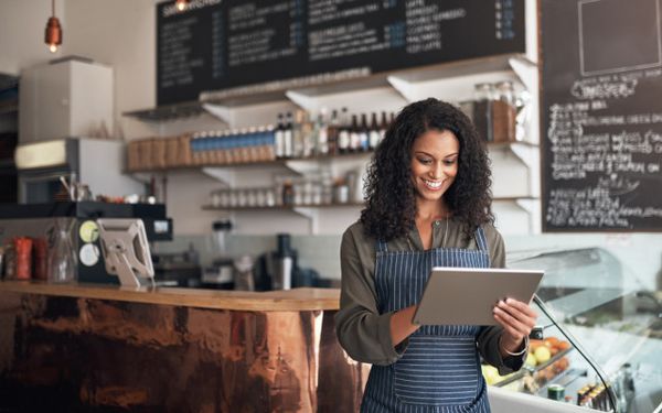 Café owner using a tablet behind the counter of an Irish coffee shop — representing SME finance, working capital loans, and support for hospitality businesses in Ireland.