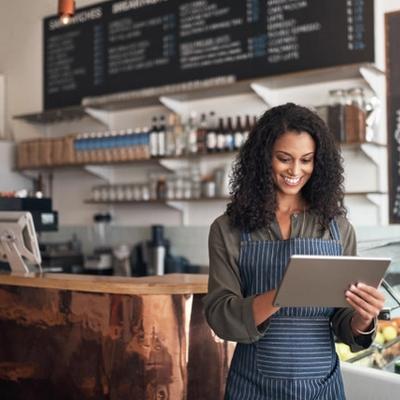 Café owner using a tablet behind the counter of an Irish coffee shop — representing SME finance, working capital loans, and support for hospitality businesses in Ireland.