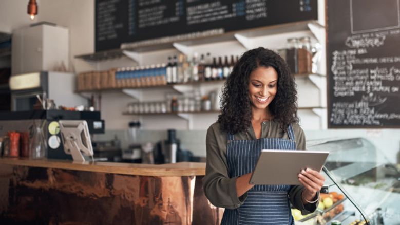 Café owner using a tablet behind the counter of an Irish coffee shop — representing SME finance, working capital loans, and support for hospitality businesses in Ireland.