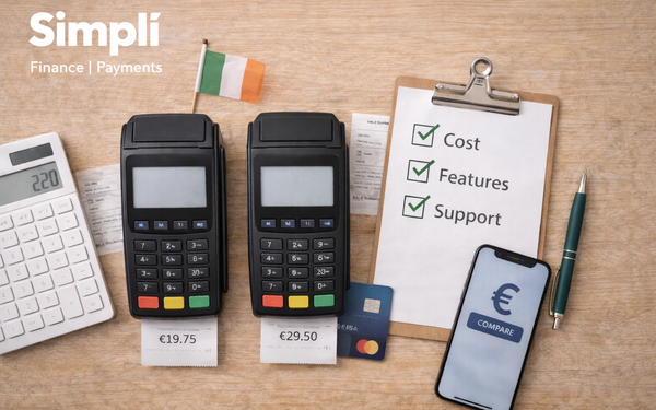 Overhead view of two black card payment terminals on a light wooden surface, each with a receipt showing different prices, beside a calculator, clipboard checklist, smartphone, pen, blue bank card, and small Irish flag, with the white Simplí Finance | Payments logo in the top left corner.