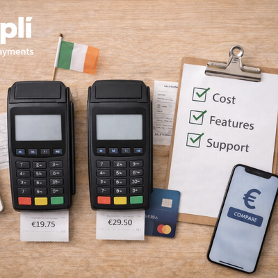 Overhead view of two black card payment terminals on a light wooden surface, each with a receipt showing different prices, beside a calculator, clipboard checklist, smartphone, pen, blue bank card, and small Irish flag, with the white Simplí Finance | Payments logo in the top left corner.