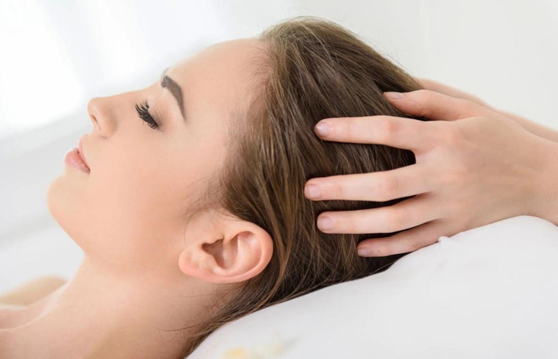 A woman getting olive oil massage on scalp