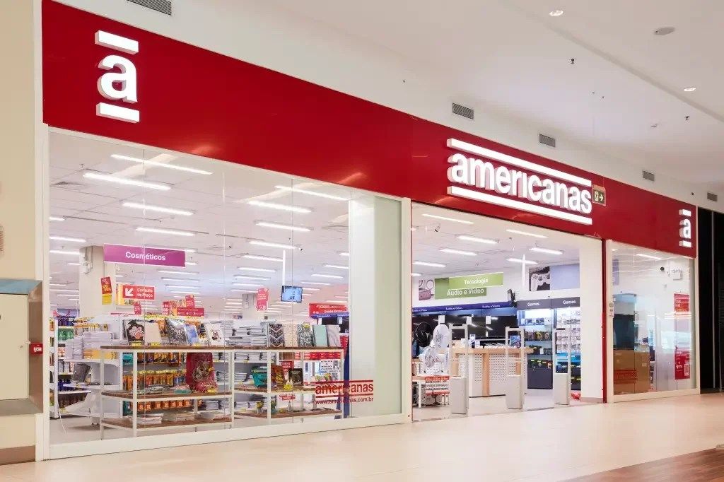 Fachada da loja Americanas com vitrine iluminada e logo visível