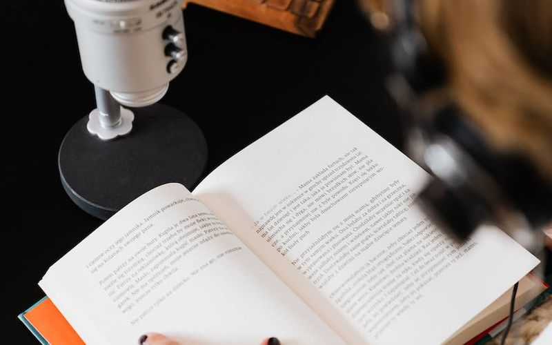 Pessoa ouvindo audiobook em fone de ouvido com dispositivo móvel