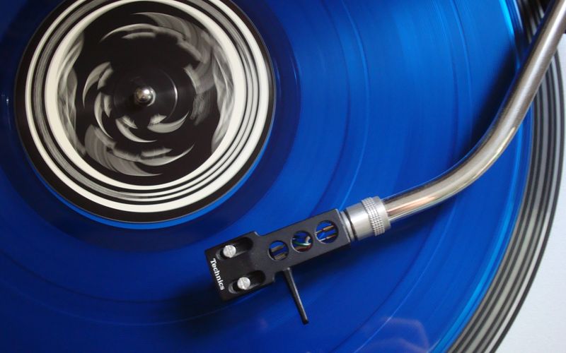 Disco de vinil ao lado de smartphone mostrando aplicativo de música