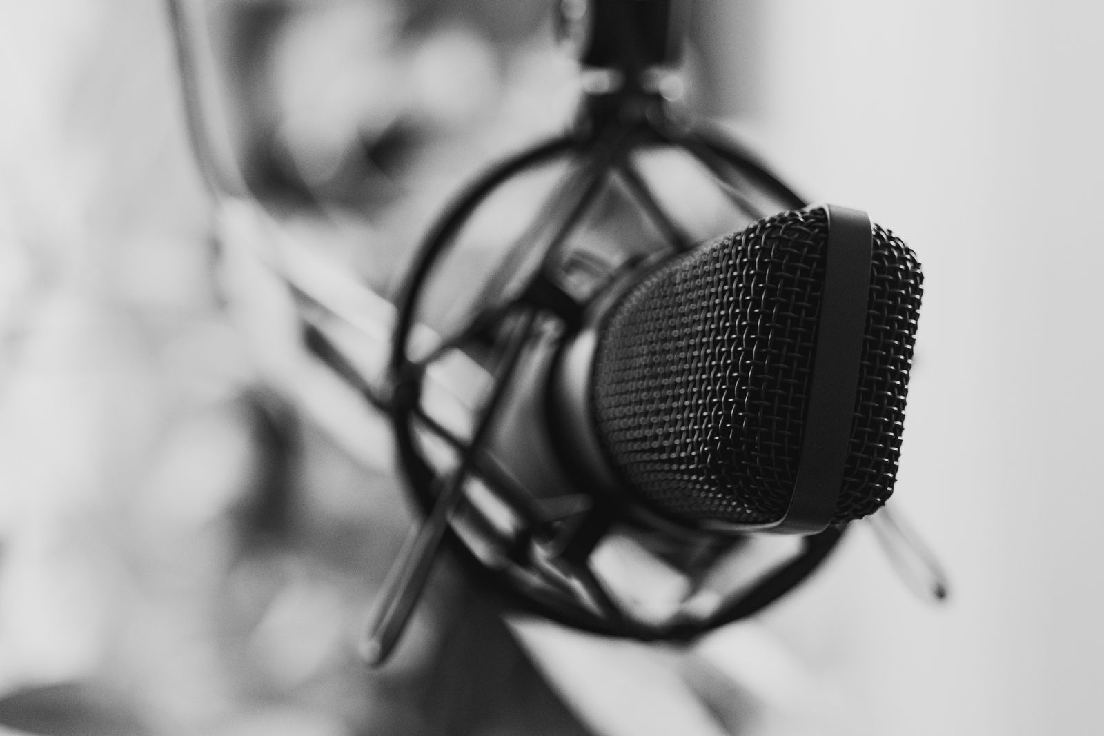 Close-up em preto e branco de um microfone de estúdio com foco seletivo, remetendo ao clima de uma redação de rádio