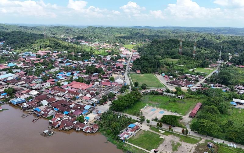 Vista aérea de uma cidade ribeirinha cercada por floresta densa e um rio, remetendo às comunidades do Alto Rio Negro amazônico